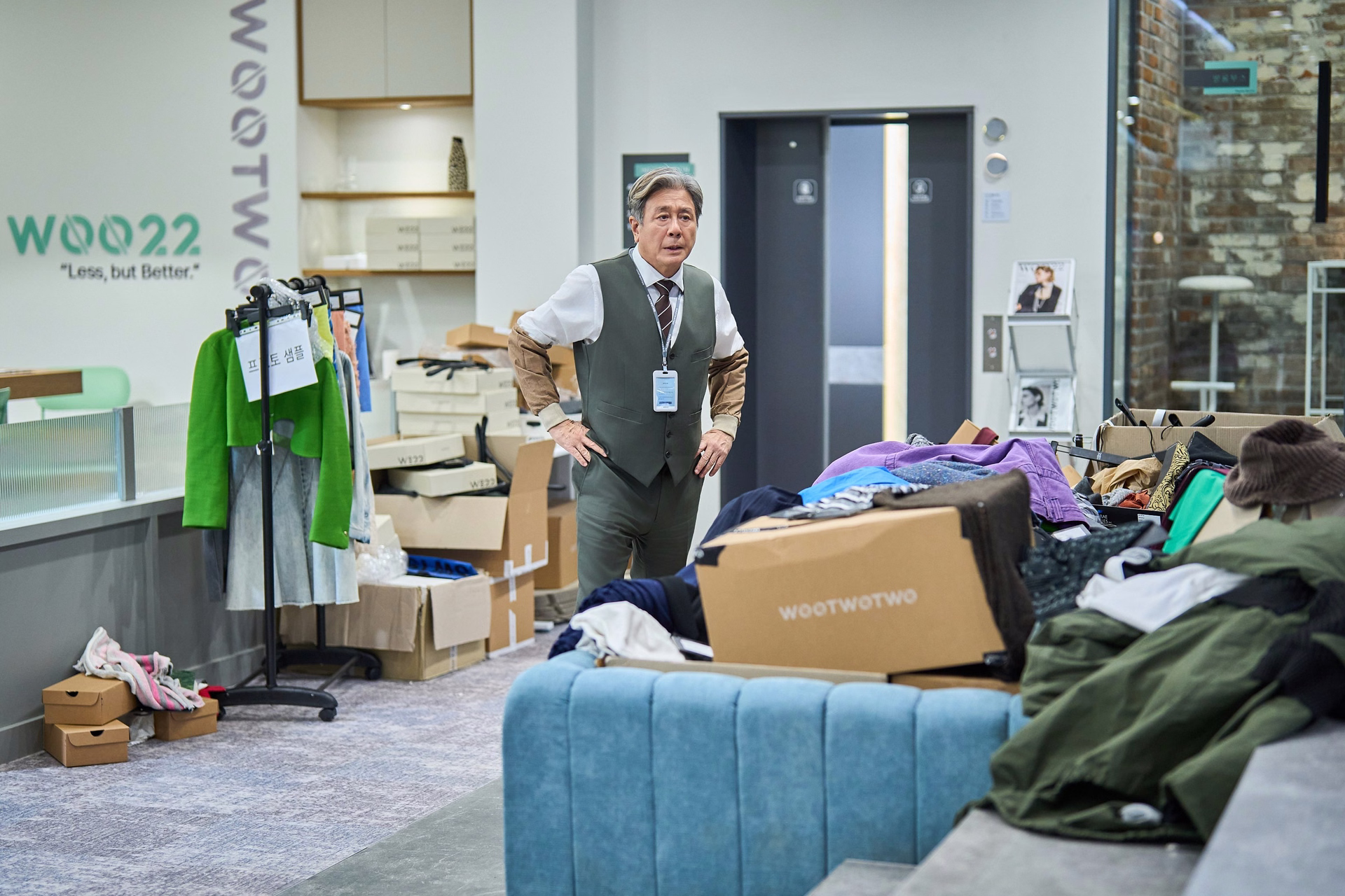 Gi Ho looking overwhelmed by piles of clothes at the fashion startup