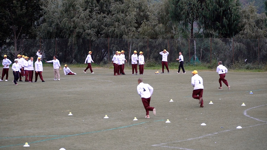 Coaches demonstrating cricket techniques to monastic participants