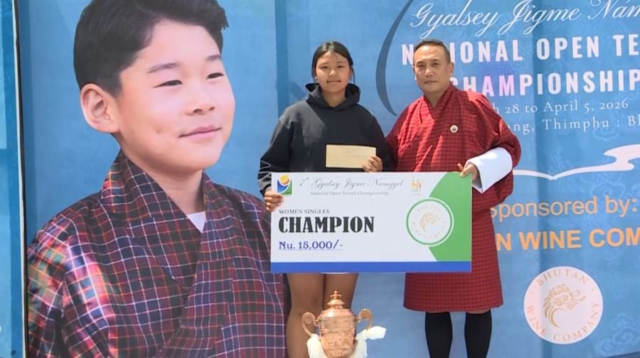Young tennis champion holding a trophy at the court